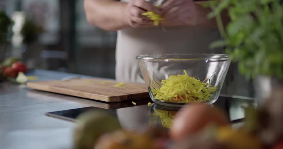 A man finely chopping vegetables and placing them in a bowl