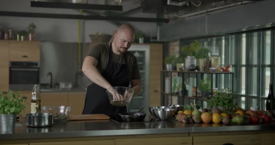 Man pouring wine and other ingredients on a frying pan