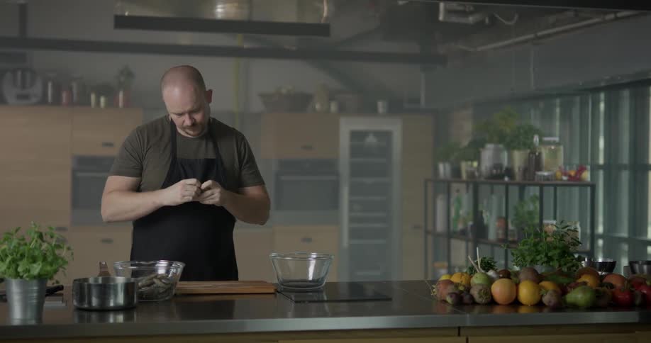A chef peels and deveins shrimp from one glass bowl and places them in another glass bowl