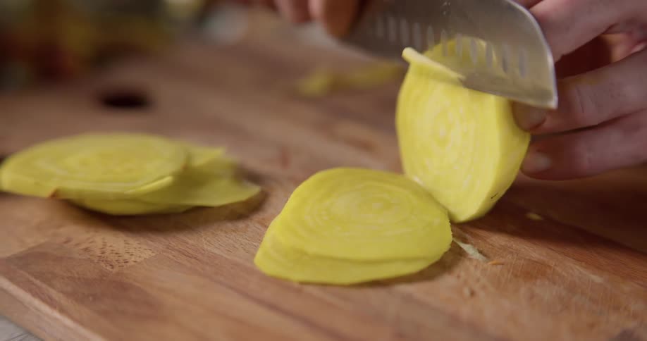 Chef slicing vegetables with a knife over a chopping board