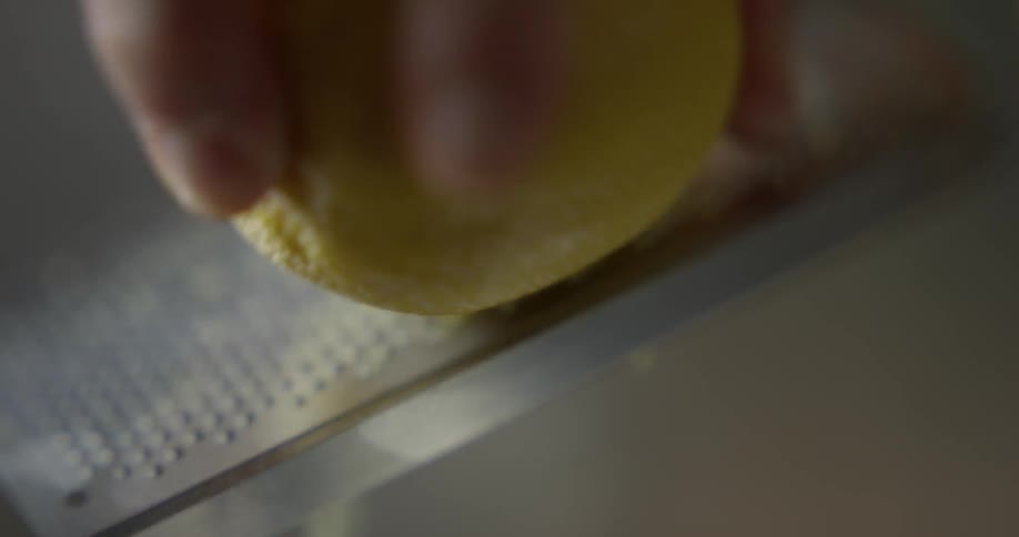 Man grates lemon with grater during daylight