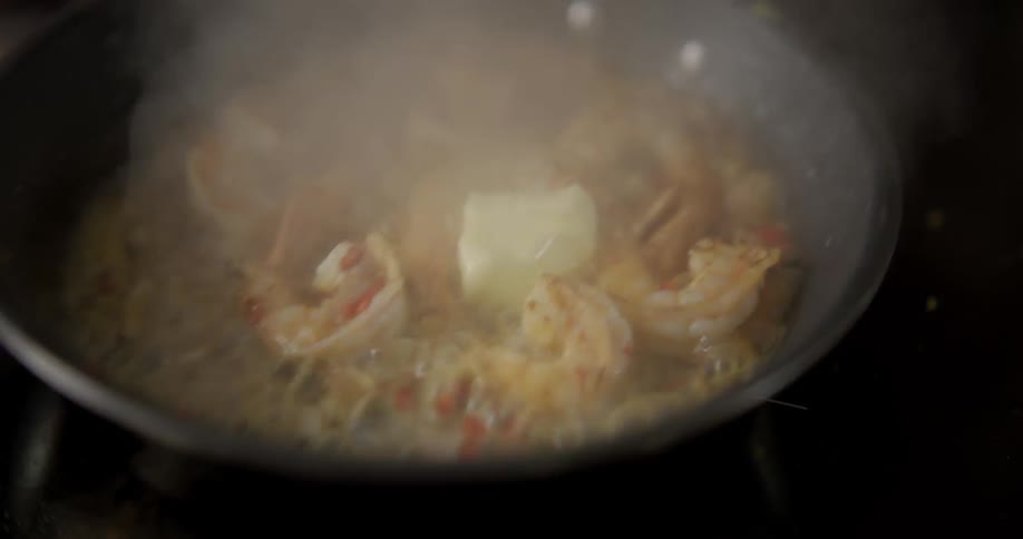 Prawns cook in a pan as it is shaken by a chef
