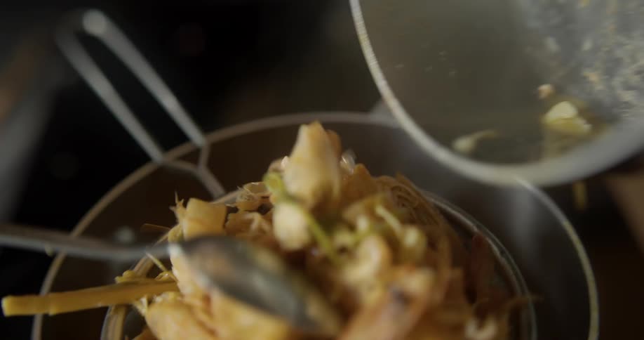 A chef pours a stir fry from a pot to a sieve