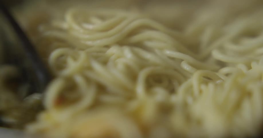 Pasta being stirred with pasta tongs