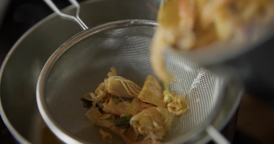 A chef puts a seafood stir fry into a sieve