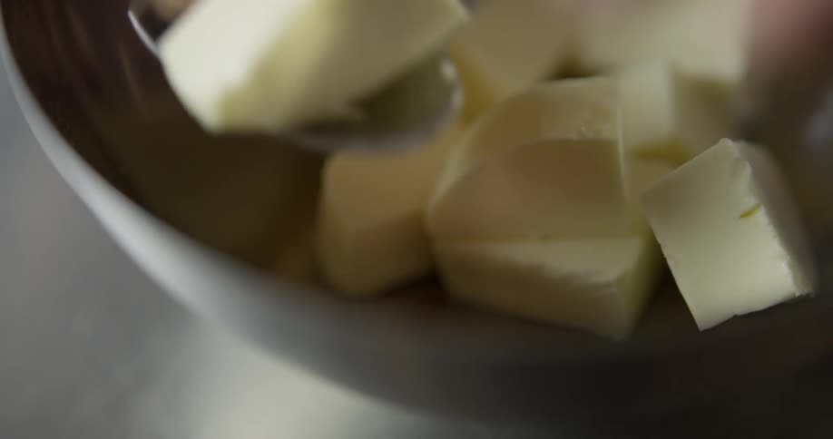 A chef scoops sliced chunks out of a bowl with a spoon