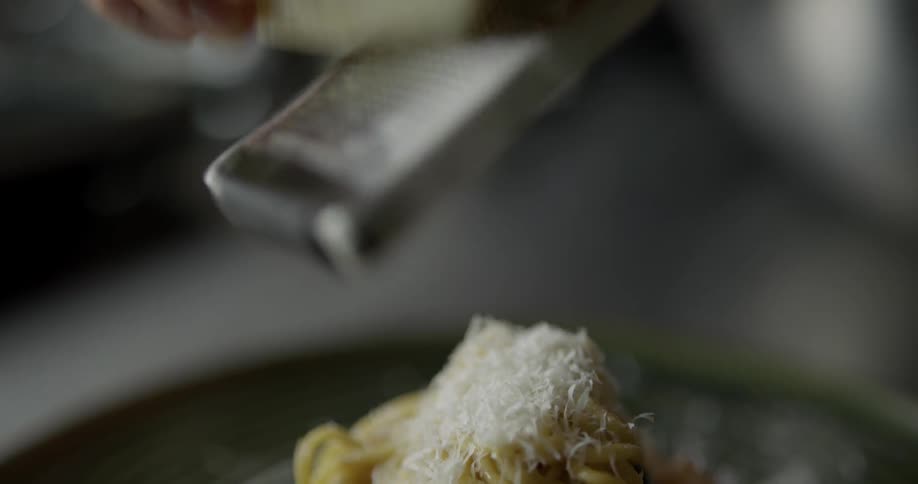 Cheese being grated onto a pasta and shrimp dish