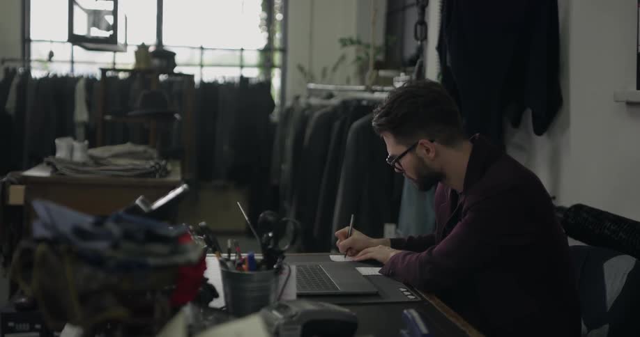 A young man sits at a desk writing