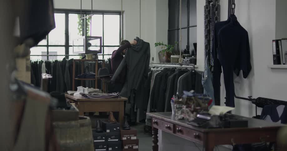 An employee in a clothing store is looking at suits