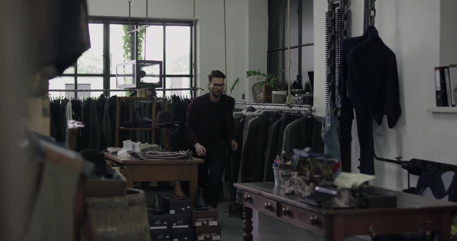 A man checks a rack of clothes then walks to his desk