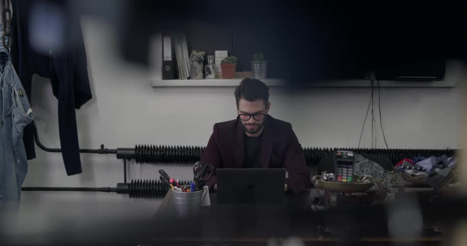 A man sitting in a clothing store on a laptop