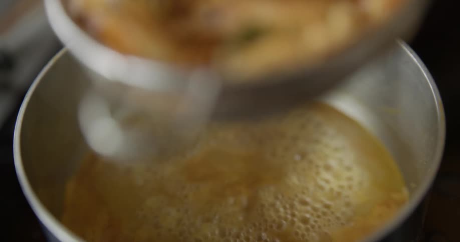Prawns being scooped out of a boiling saucepan
