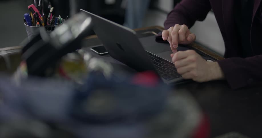 A person working on a laptop on a crowded desk