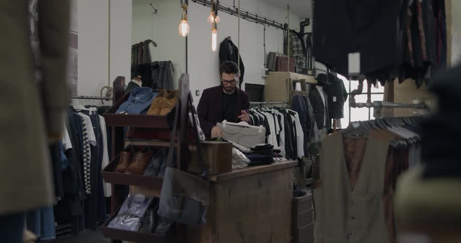 A man working in a clothing store gathers clothes