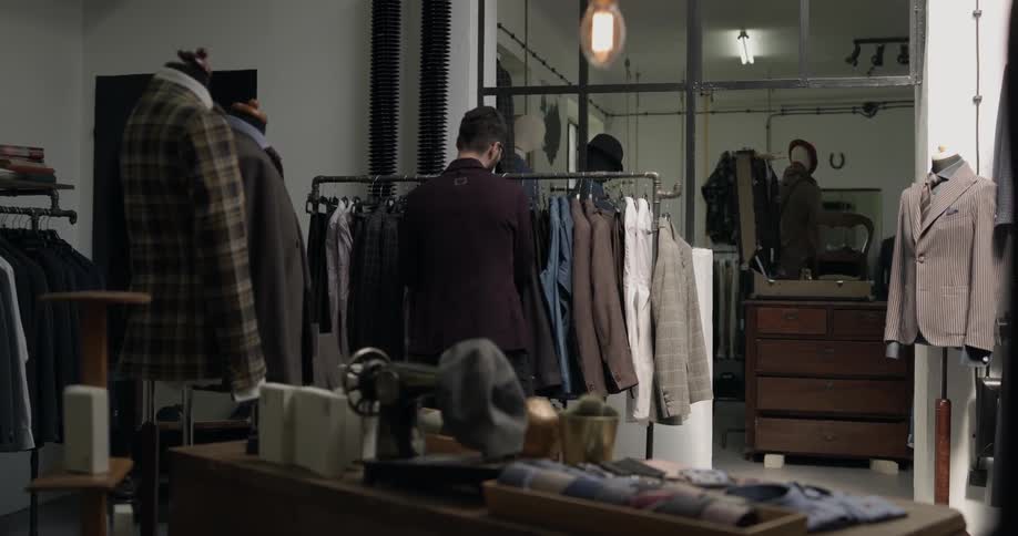 A tailor working on his workshop filled with suits and mannequins