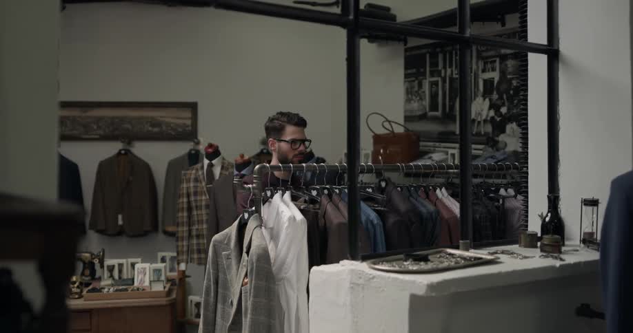 A man hangs up a jacket on a rack in a clothes shop