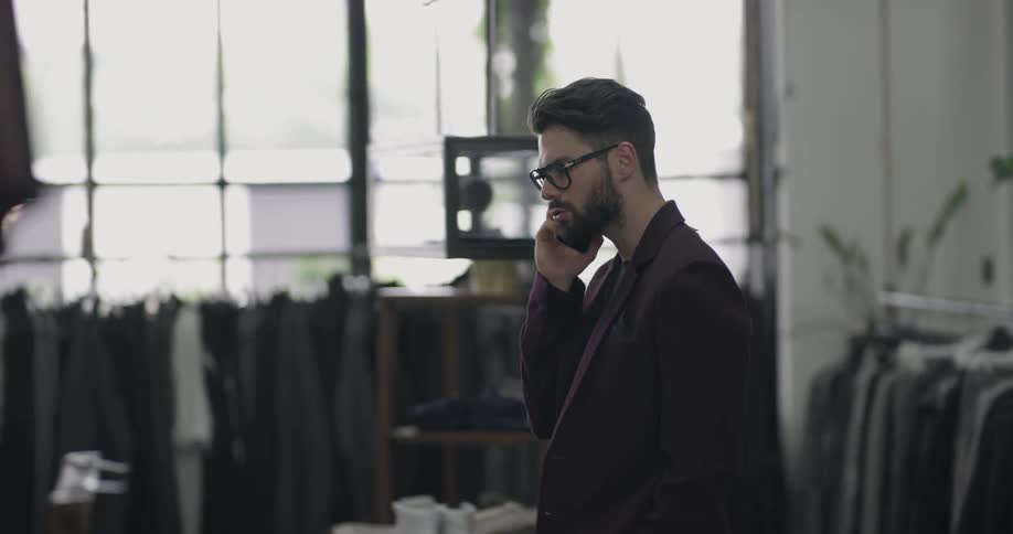 A man speaking on a smart phone in a clothing shop