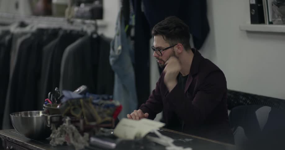 Salesman sits at desk in mens suit shop