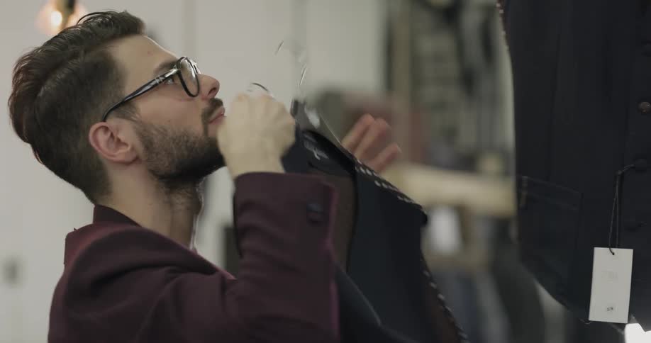 A man retrieving vests from an overhead clothing rack