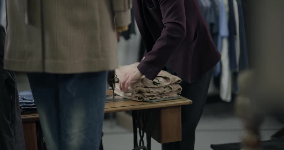 A man organizing shirts on a table in a clothing shop