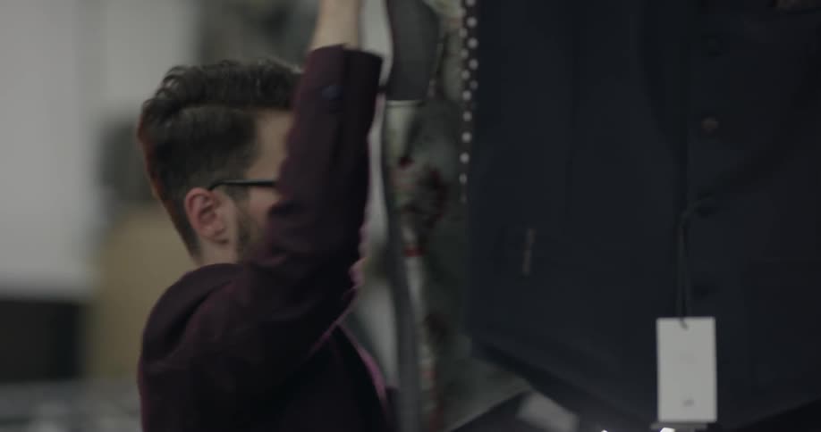 A man in a suit looking at a vest on a hanger