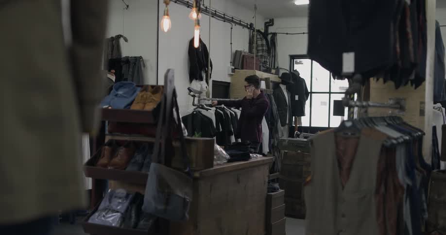 Man talks on cell phone while looking through suits on clothes rack
