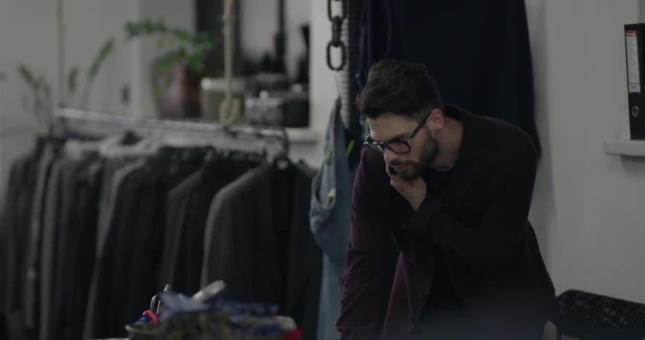 A man talks on a cellphone in a clothing store
