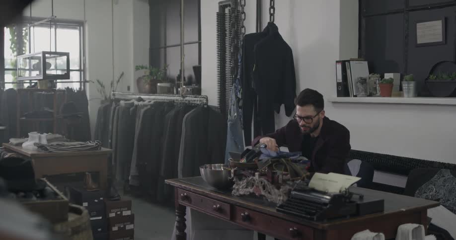 A man sits at a desk in clothing store
