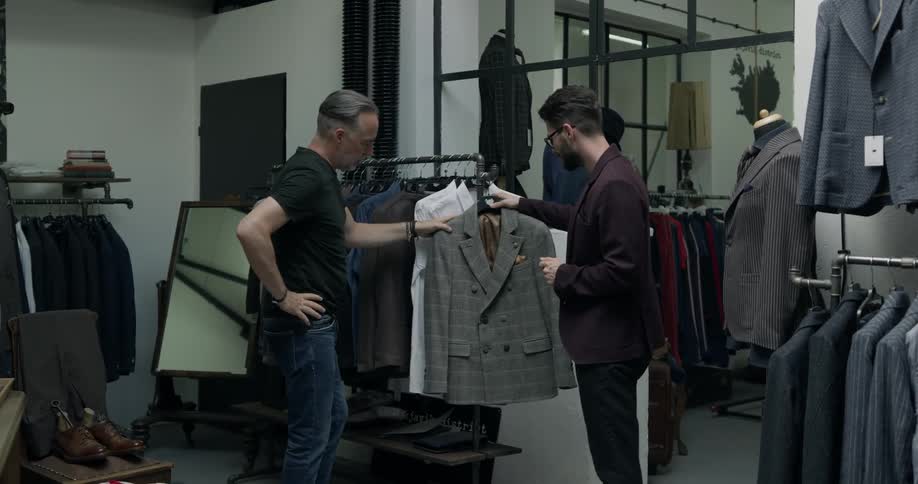 A examining a clothing rack in a clothing store before being approached by an employee