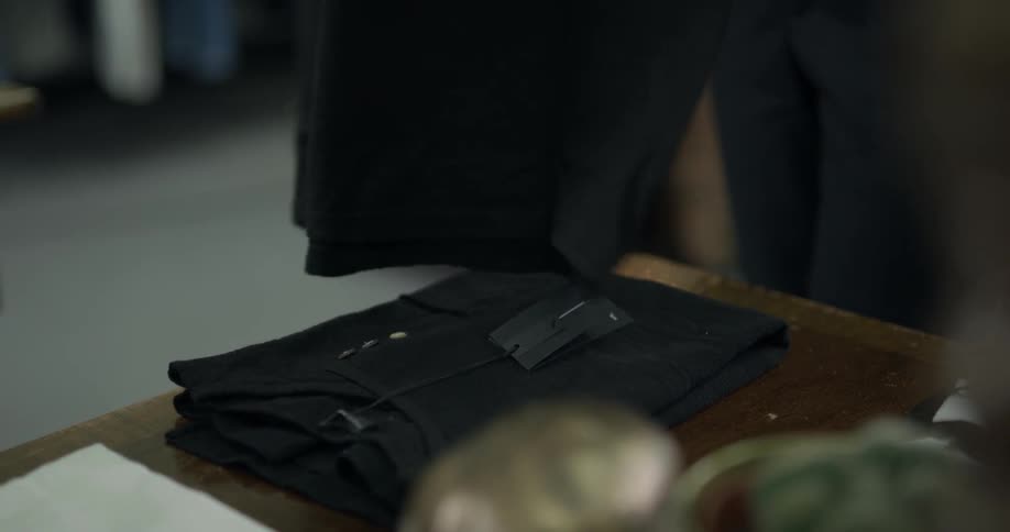 Employee folding and arranging shirts on a wood table in a shop