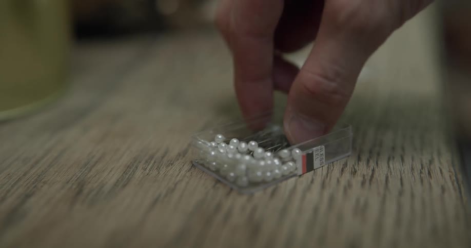A man gets a pin out of a box of pins