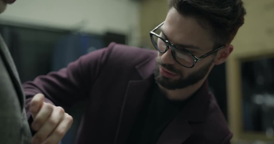 Shop assistant helps customer in choosing blazer jacket in clothing store