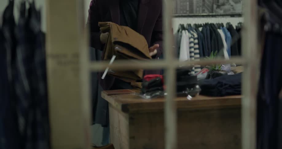 Salesman folds slacks in suit boutique