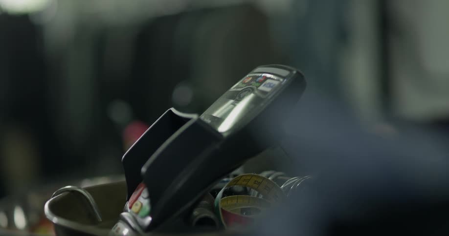 A man holds up his phone to a credit card reader at a store and is likely using some sort of payment directly from his smart phone
