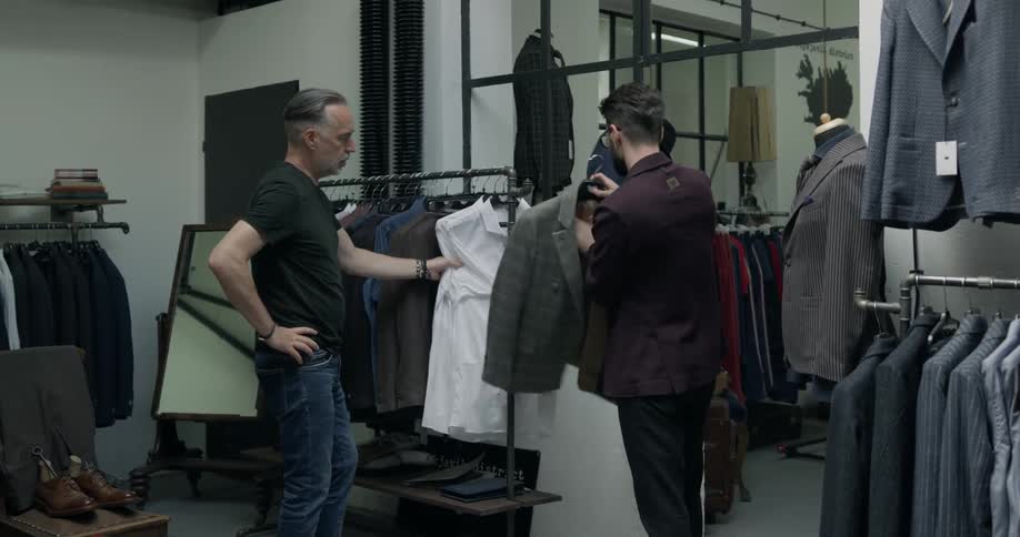 Two men in a clothing store looking at a suit jacket