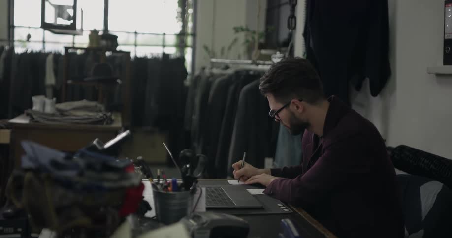 A man writing a note on a piece of paper in his shop