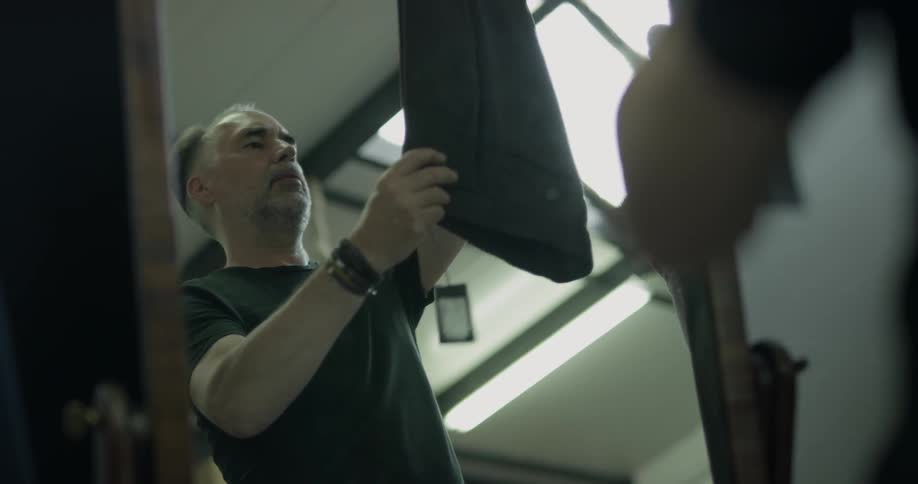 A man looks at a pair of pants in front of a mirror