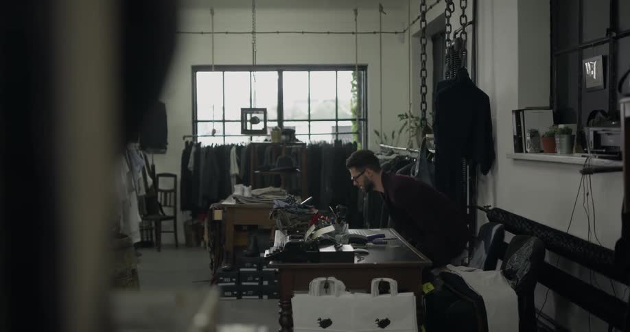 A male sitting at desk in a clothing tailoring business