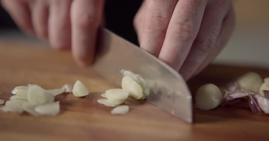 Man cuts shallot fast on cutting board during daylight