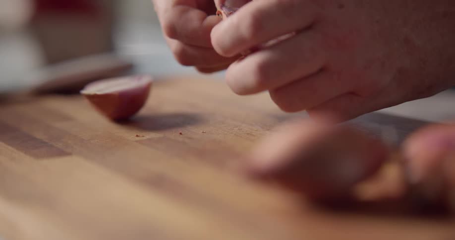 A person cutting open garlic on a counter using a knife