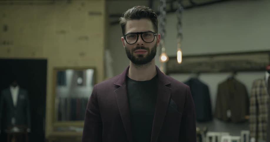 A man stands in the middle of a men's clothing store looking at a camera