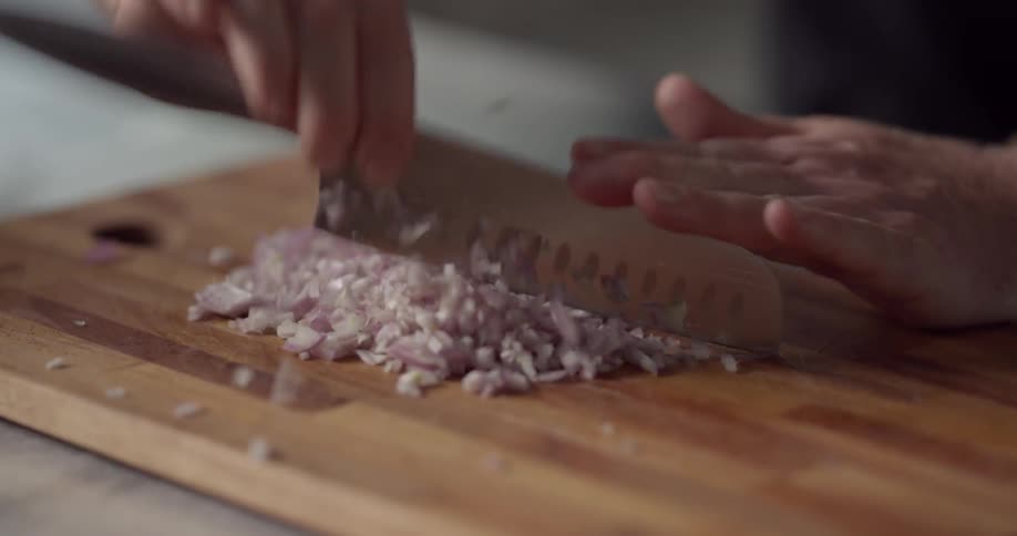 Onions being diced on a wooden cutting board