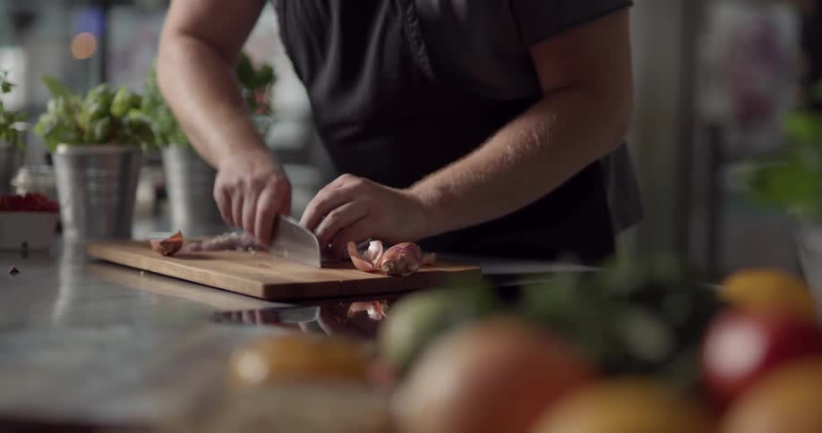 A man cutting onions on a wooden cutting board
