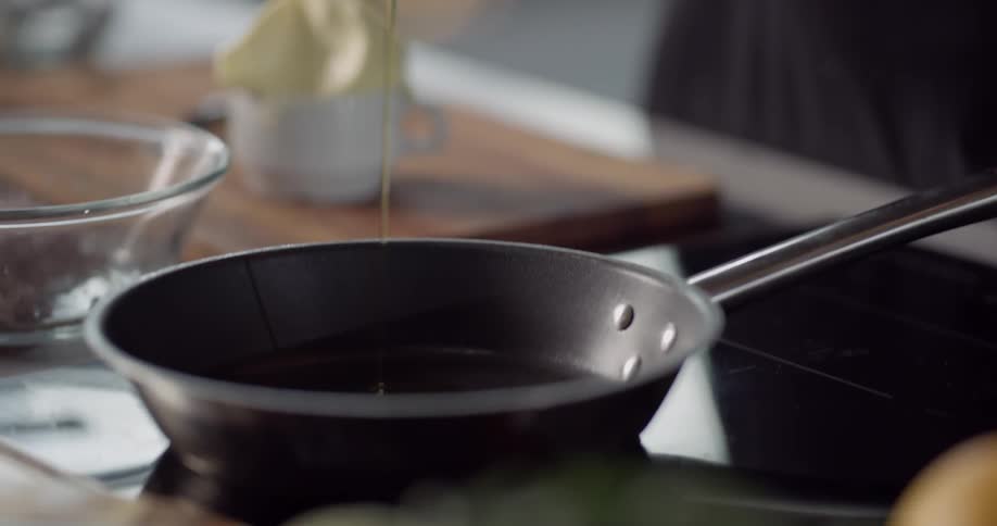 Cook opening bottle of oil then pouring in frying pan