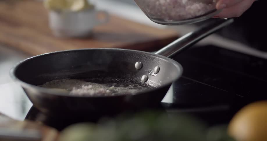 Cook placing chopped ingredients on a frying pan