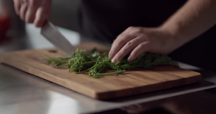 A person begins cutting some greens