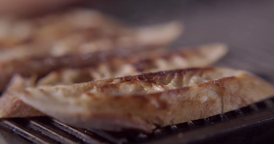 Slices of bread being flipped and toasted on a griddle pan