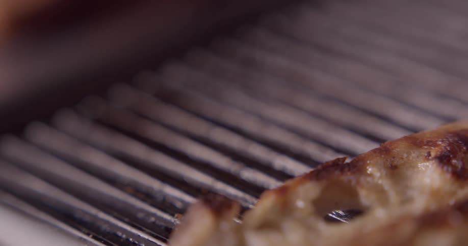 Pieces of bread being taken off of a grill