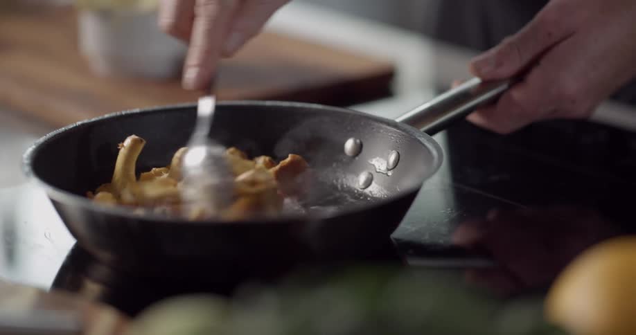 A person mixes the food in the pan