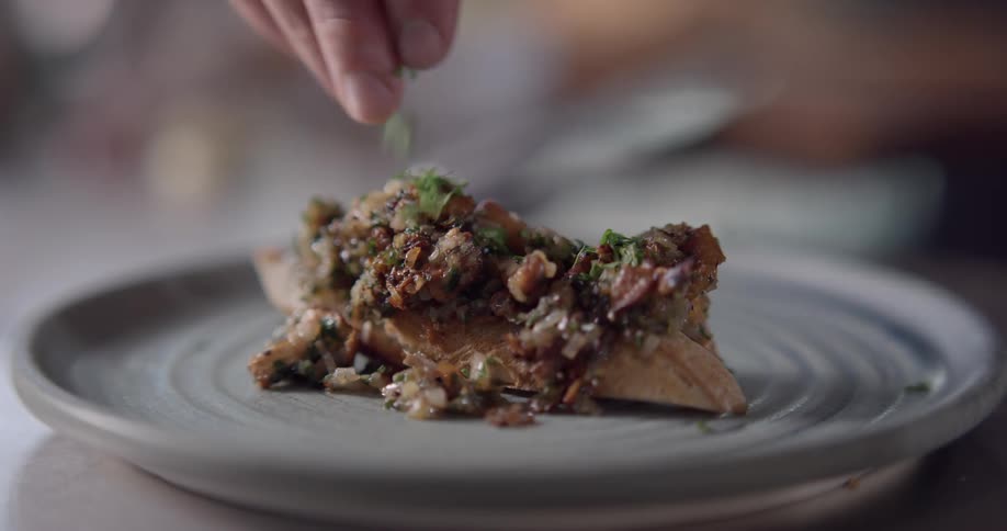 Chef garnishing a plate of chicken breasts